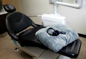 A dentist's chair with a weighted blanket and noise canceling headphones provided to relax.